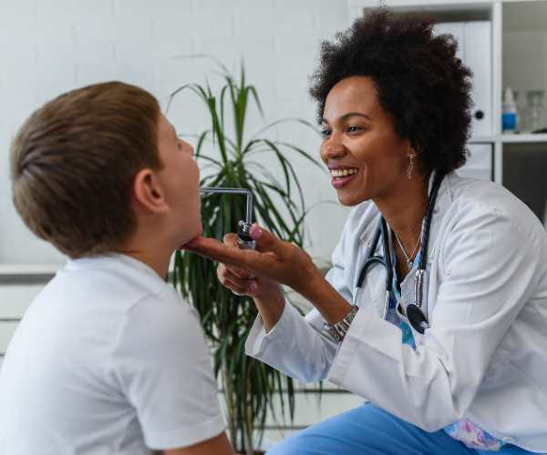 black physician woman doctor giving young kid a checkup