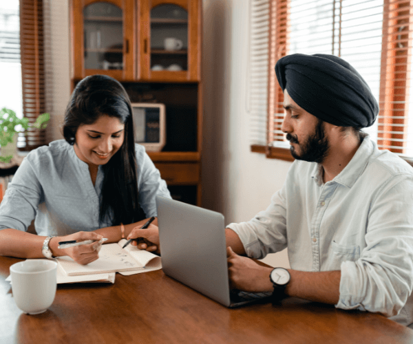 millennial indian couple talking about finances with accounting notes and laptop